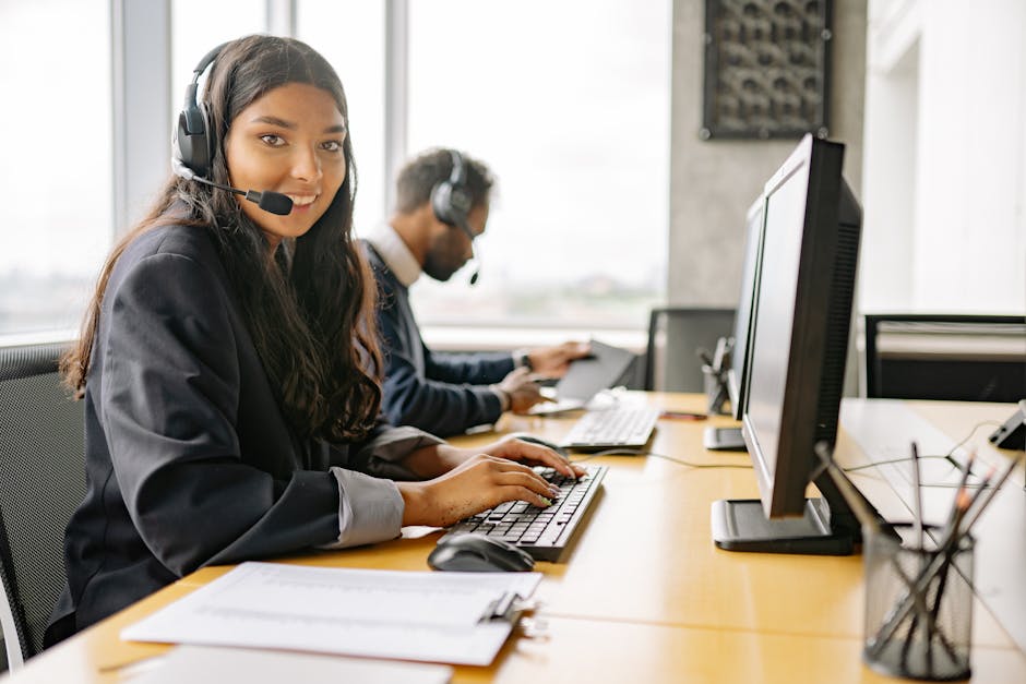 Smiling call center agents in an office providing customer support on computers.